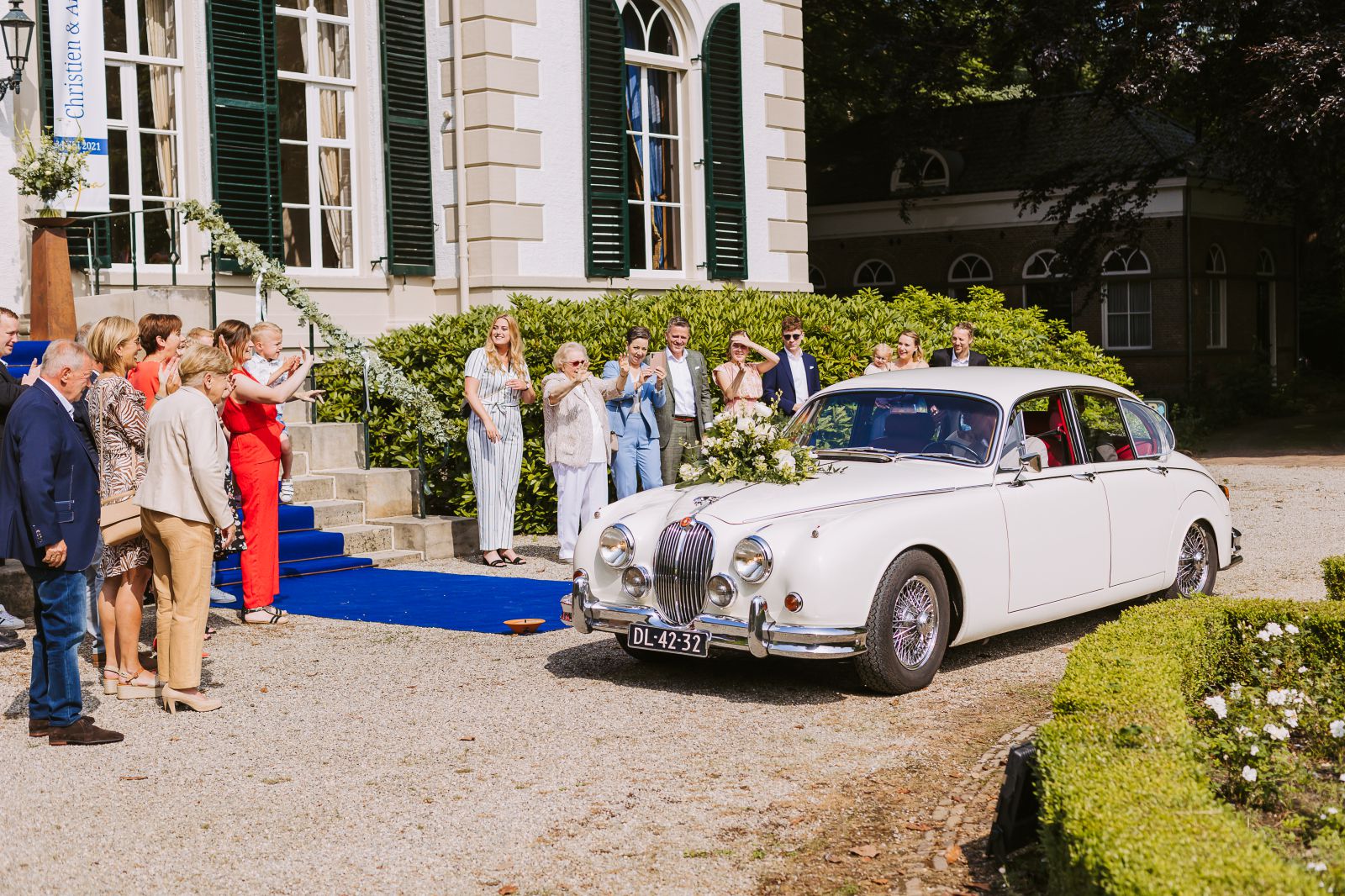 Bruidspaar verlaat een landhuis met klassieke trouwauto bij Zwolle