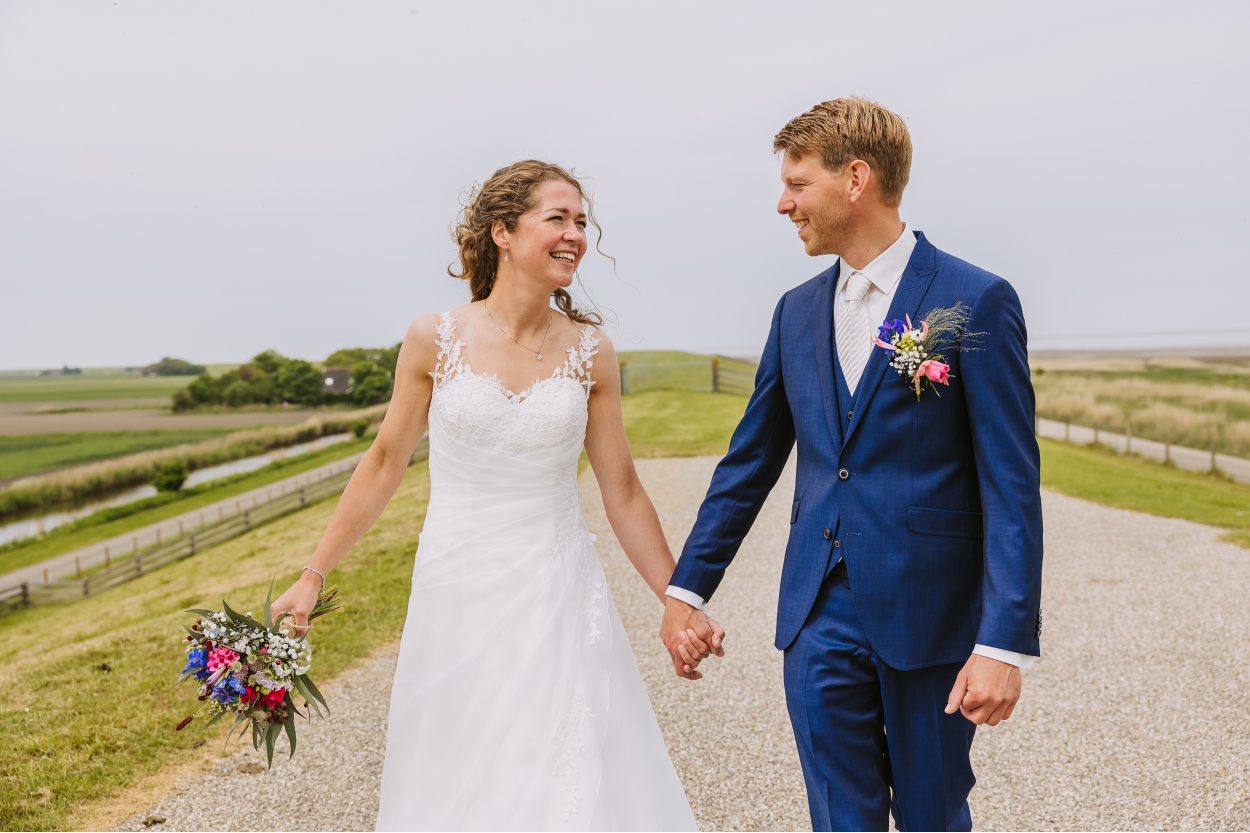Bruidspaar loopt hand in hand over een Friese zeedijk