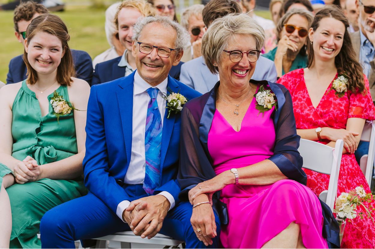 Lachende gasten op de eerste rij tijdens de ceremonie