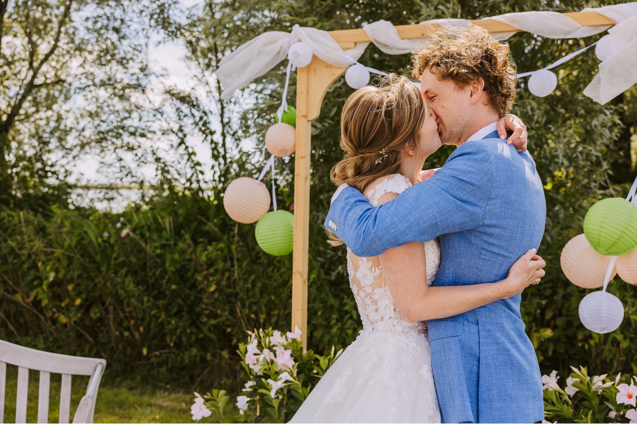 Kus onder de bloemenboog tijdens de ceremonie